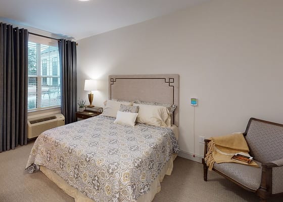 A cozy private resident room with a bed and chair