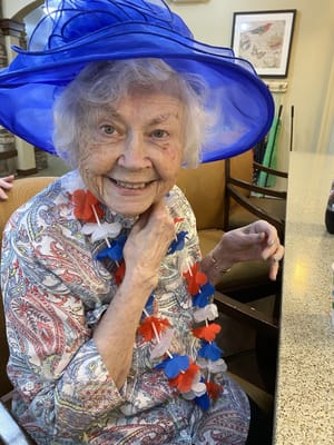Resident wearing a festive hat and leis during a celebration