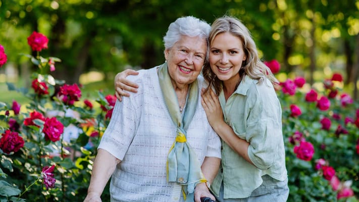 Senior resident and staff smiling in a garden
