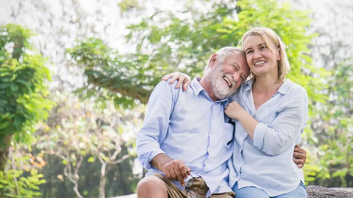 A smiling couple enjoying time outdoors in a senior living community.