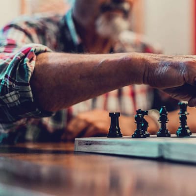 Resident playing chess in an indoor activity area