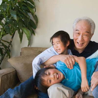 Elderly man playing with two children in a cozy room