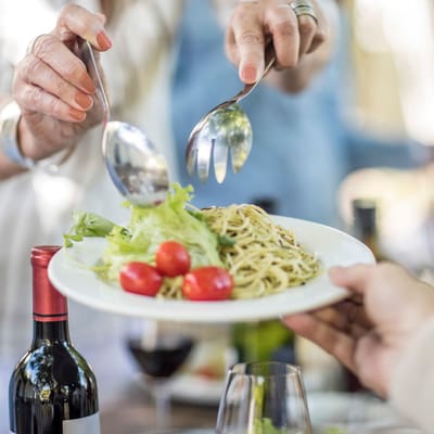 Hands serving food with wine on the table