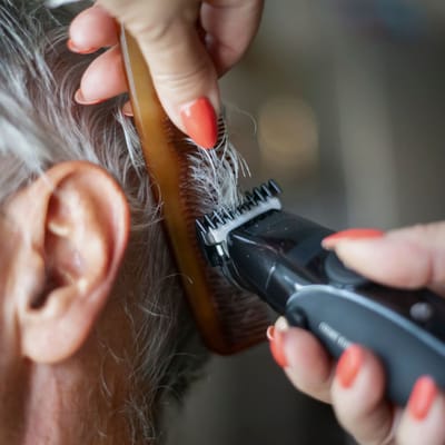 Caregiver trimming hair in a personal grooming session