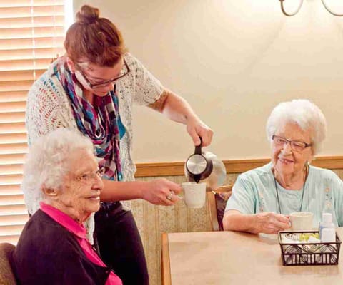 Staff pouring coffee for residents in a cozy lounge