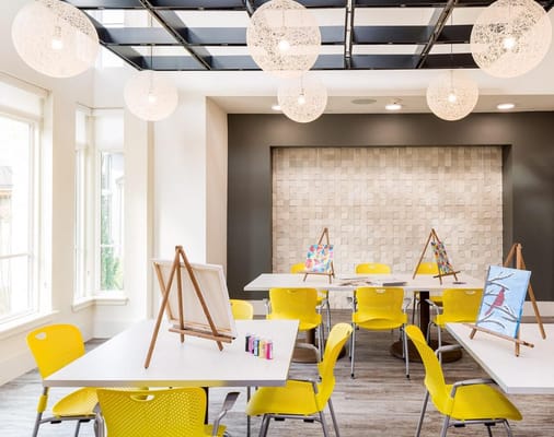 Bright activity room with art easels and yellow chairs