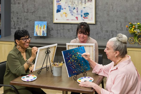 Residents enjoying a painting activity in a bright activity room