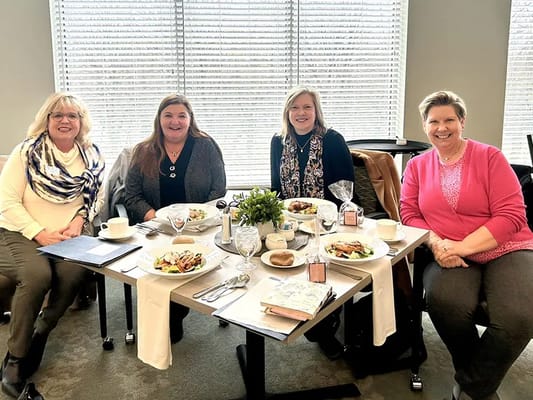 Four staff members enjoying lunch together in a bright dining area