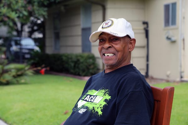 Senior man smiling outdoors in a green space