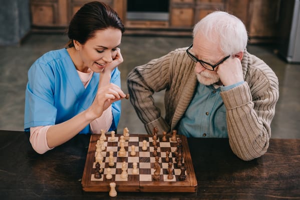 Care staff playing chess with a resident