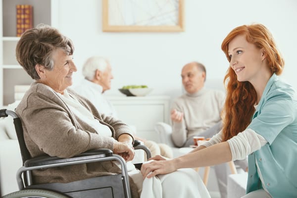 A caregiver assisting a resident in a bright common area