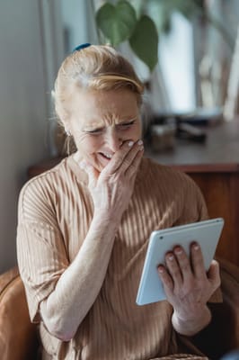 Senior woman reacting joyfully while using a tablet
