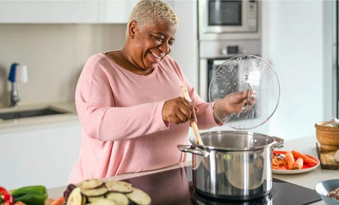 Resident happily cooking in a bright kitchen