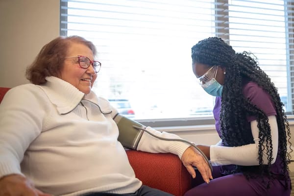 Nurse taking blood pressure of a smiling resident