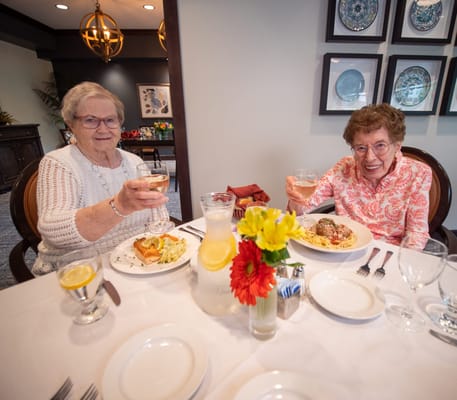 Two residents celebrating with dinner and drinks in a dining area