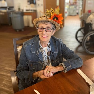 Resident seated at a dining table with a hat