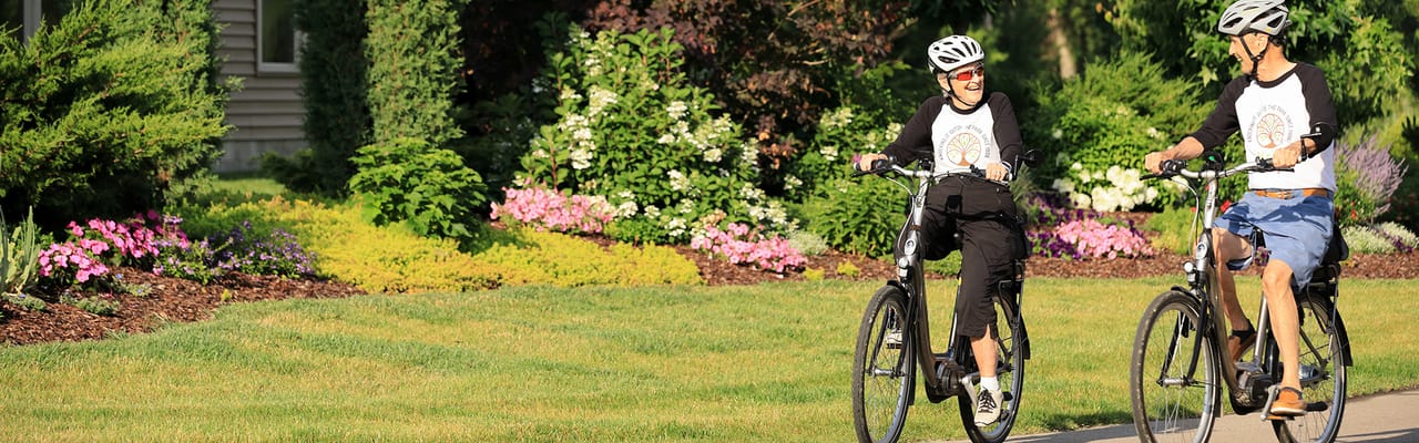 Two residents biking along flower beds in a garden