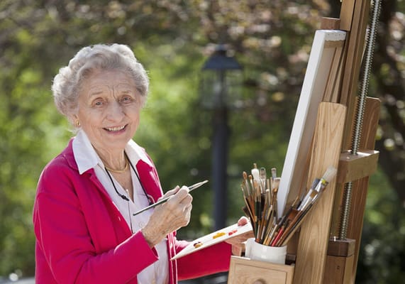 Senior woman painting outdoors with art supplies