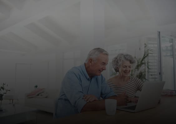 Two seniors enjoying time on a laptop in a bright room