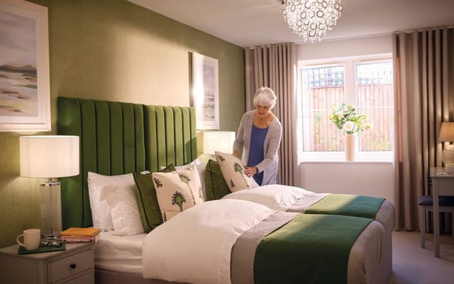 A resident arranging pillows in a cozy twin bedroom
