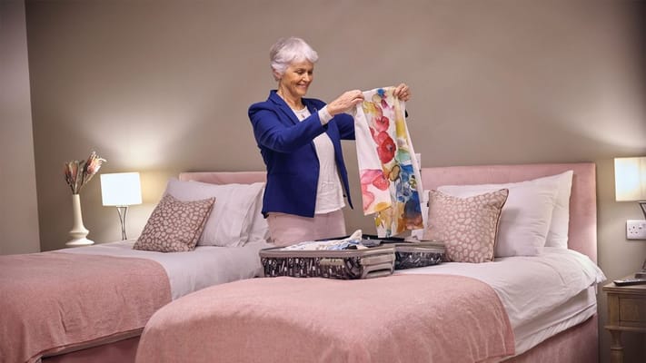 A resident unpacking clothes in a bedroom