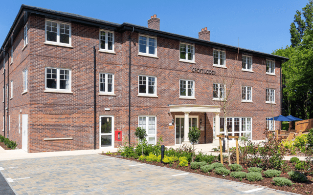 Exterior view of a senior living facility with gardens and seating