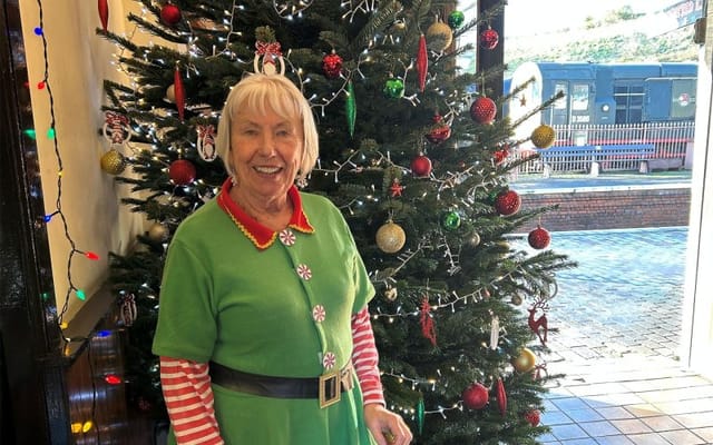 Resident in festive attire next to Christmas tree