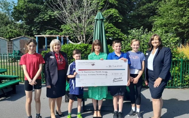 Group photo at an outdoor event with a check presentation