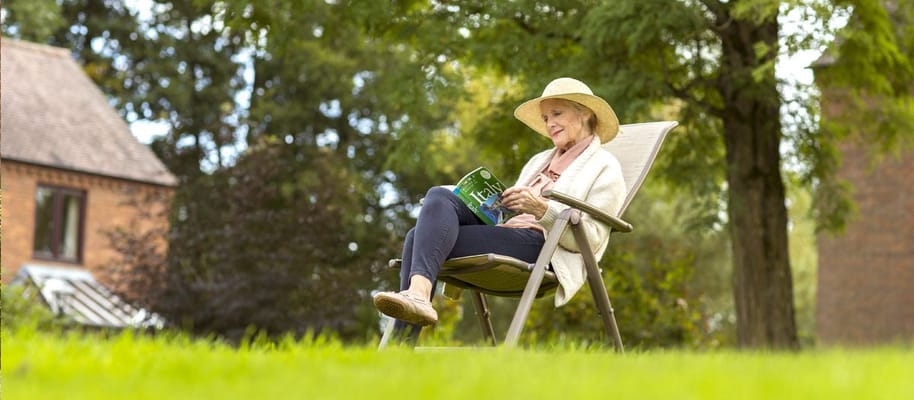 A resident reading a book in a garden