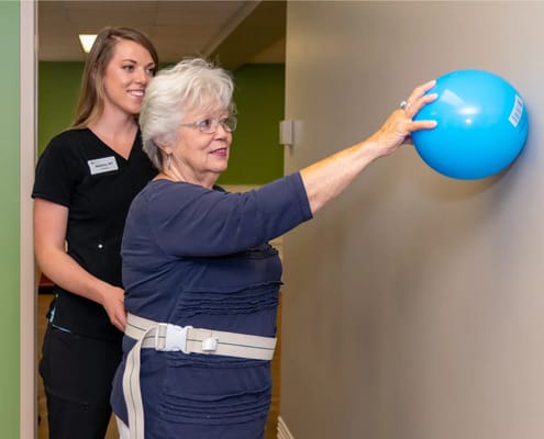 Therapist assisting a resident with a blue exercise ball