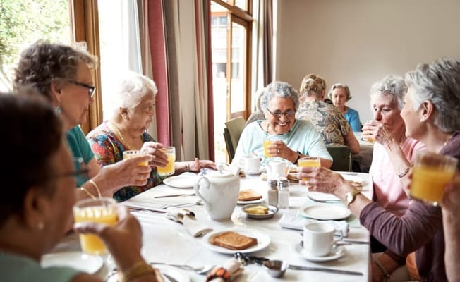 Residents enjoying juice and breakfast in a dining room