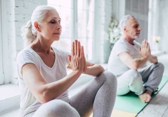 Seniors practicing yoga in an indoor space