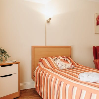 Cozy resident room with striped bedding and armchair