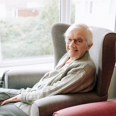 Elderly resident smiling in a cozy armchair