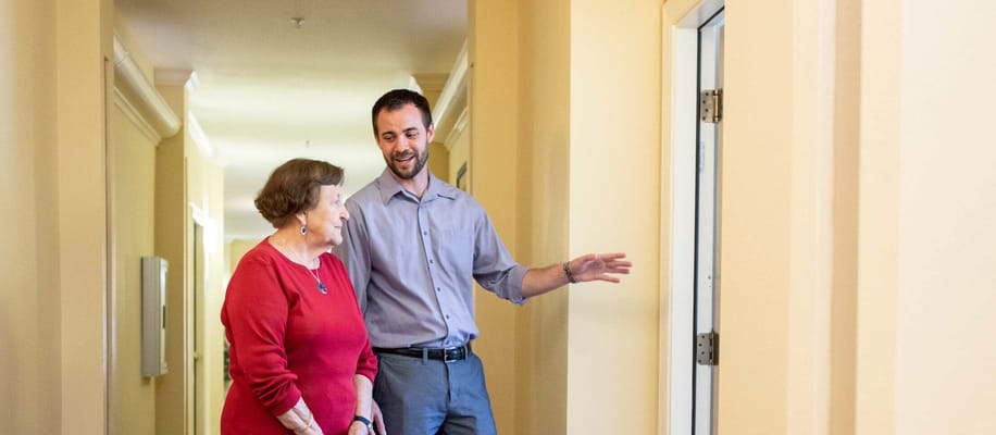 Staff member assisting a resident in a hallway
