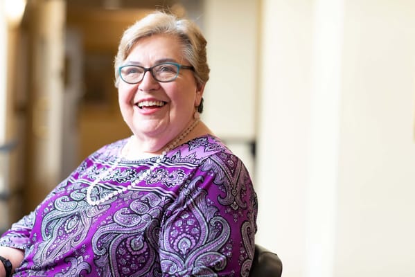 Smiling resident in a colorful blouse within the facility