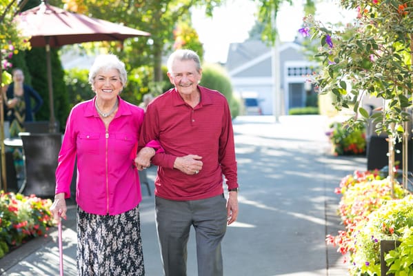 Two seniors walking together in a vibrant garden