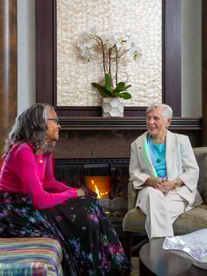 Two residents enjoying a conversation by the fireplace