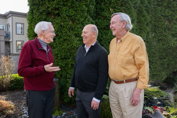 Three men chatting outside in a garden area