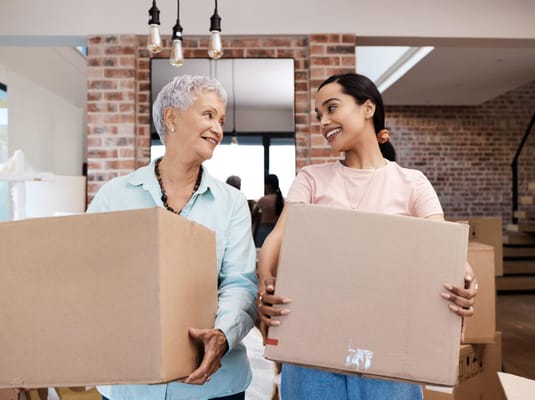 A resident and staff member carrying boxes in a welcoming interior