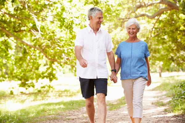 A couple walking hand in hand on a sunny path