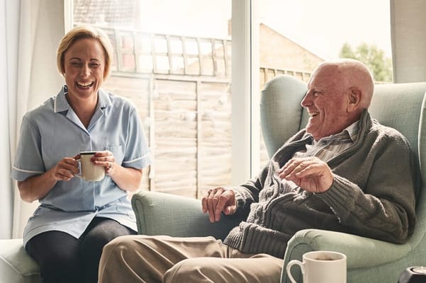 A caregiver sharing a laugh with a resident in a cozy room