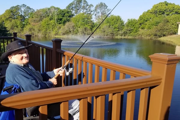 An elderly man fishing by a serene pond