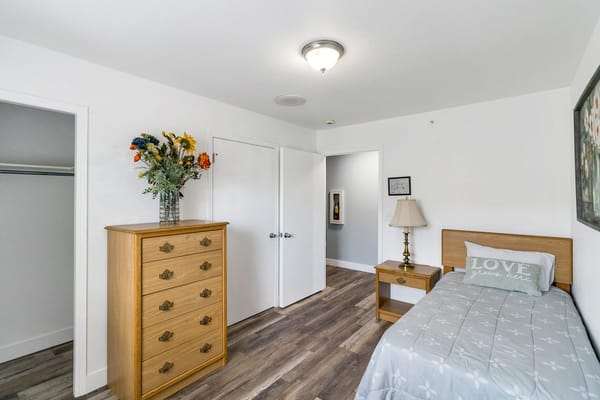 A cozy resident room with a bed and dresser