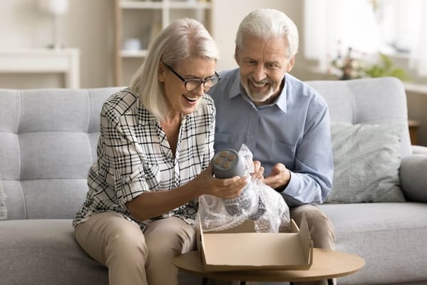 Seniors happily unboxing a gift in a living room