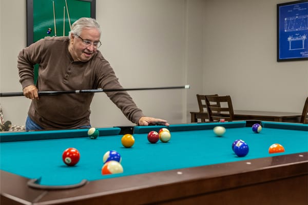 Resident playing billiards in an activity room