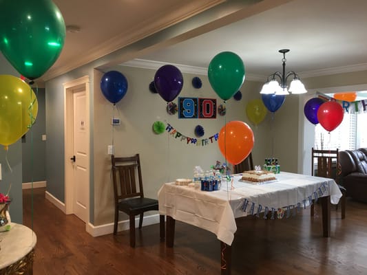 Decorated room for a 90th birthday celebration with balloons and cake