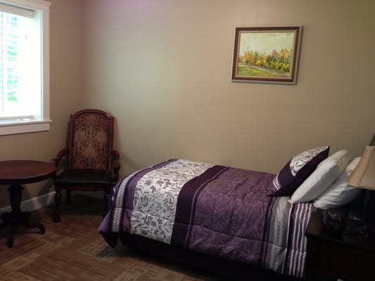 A cozy resident room with a bed and chair