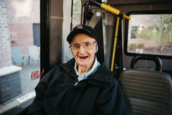 A senior man smiling in a facility transport bus