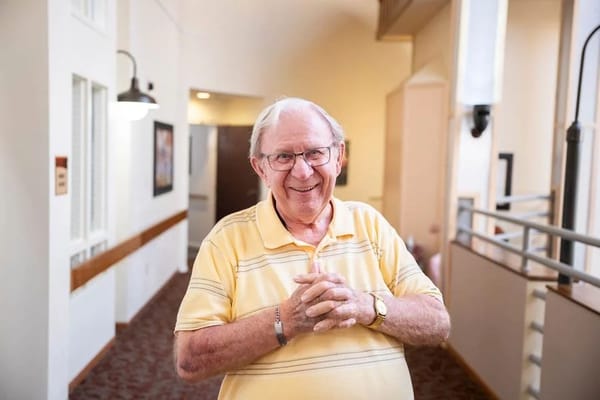 A smiling resident in a well-lit corridor.
